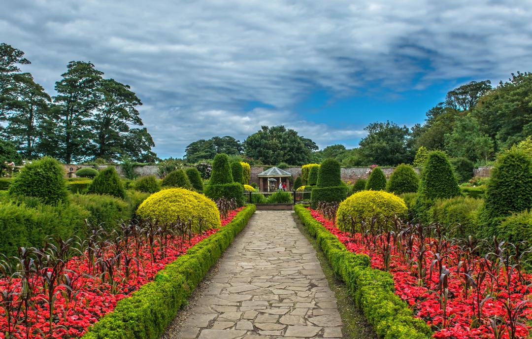 Manicured gardens with red flowers and toparie at Sewerby Hall